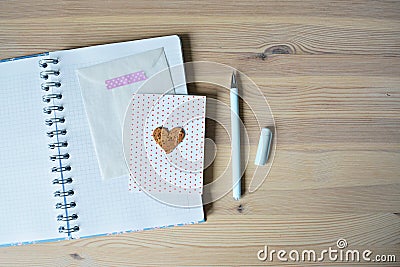 Open notebook, white envelope, card with heart and blue pen Stock Photo