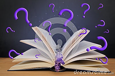 Open paper book with magic glow and question marks, concept of magic and mystery, on a wooden table, a sprig of lavender lavender Stock Photo