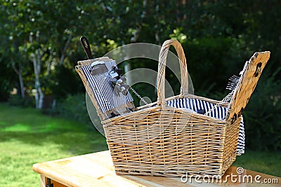 Open picnic basket on wooden table Stock Photo