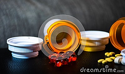 Open pill bottles on table top with red gel caps and yellow pills Stock Photo