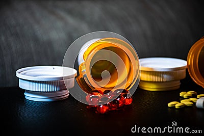 Open pill bottles on table top with red gel caps and yellow pills Stock Photo