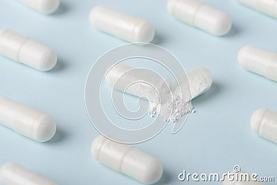 Open pill capsule with white powder substance macro among closed Stock Photo