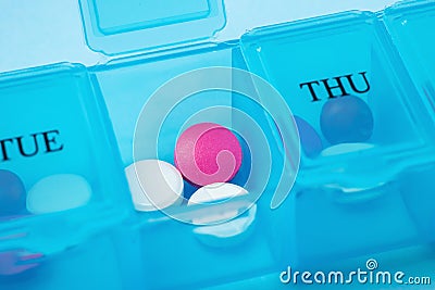 Open pill organizer with pills on blue background Stock Photo