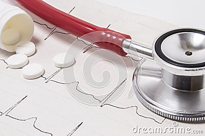 An open plastic container for tablets, which spilled white pills on a printed electrocardiogram as a background and a stethoscope Stock Photo