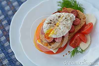 Open poached egg, sausage, tomato, feta cheese, dill, bread - fast snack Stock Photo