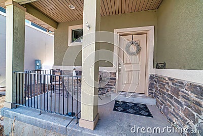 Open porch with railings at house facade with front door decorated with wreath Stock Photo