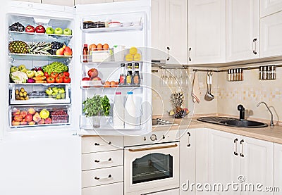 Open refrigerator filled with fresh fruits, vegetables and milk Stock Photo