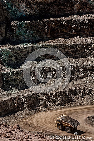 Open rock mine with different layers and a truck carrying rocks Stock Photo