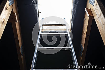 An open roof hatch in the attic for a chimney sweep, a standing ladder in the window. Stock Photo