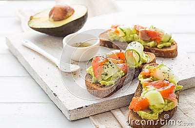 Open sandwich or toast. Grain bread with salmon, white cheese, avocado, cucumber and spinach. Healthy snack, healthy fat and omega Stock Photo