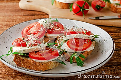 Open sandwiches with fresh mozzarella, tomatoes and arugula. Italian food Stock Photo