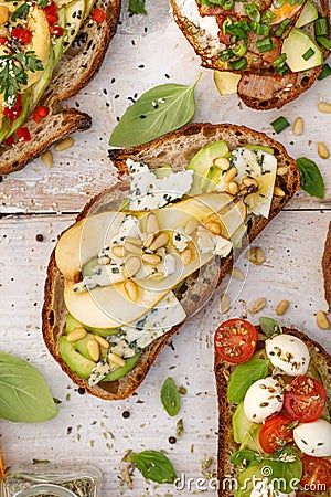 Open sandwiches, in the middle of board an open avocado sandwich made of slice of sourdough bread with the addition of pear, blue Stock Photo