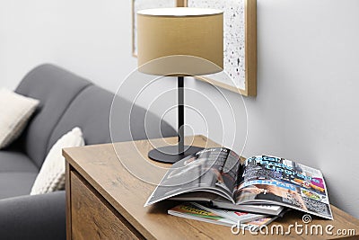 Open sports magazine and lamp on cabinet in living room Stock Photo