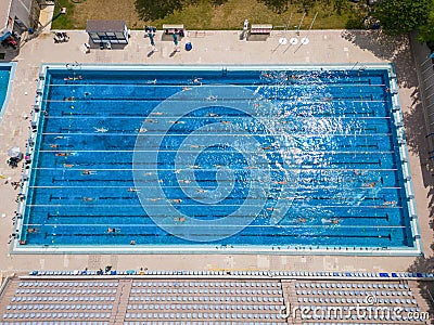 The open sports swimming pool glistened under the bright sun as people swimming in its inviting waters. Stock Photo