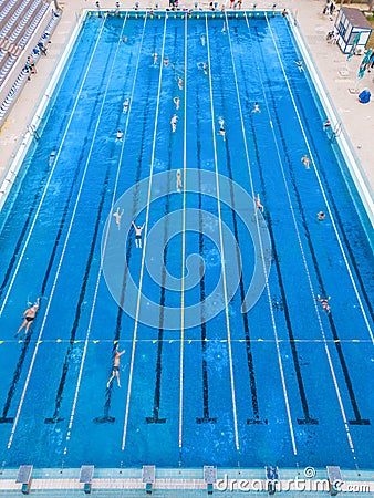 The open sports swimming pool glistened under the bright sun as people swimming in its inviting waters. Stock Photo