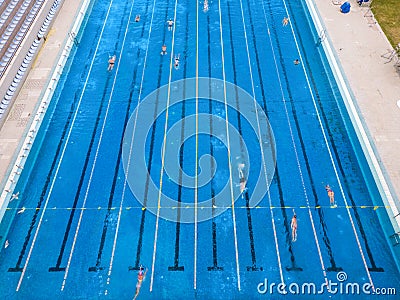The open sports swimming pool glistened under the bright sun as people swimming in its inviting waters. Stock Photo