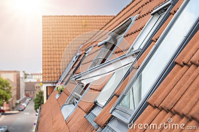 Open ventilation waterproof rooftop window exterior against sunny sky light. Velux style roof with red brick tiles Stock Photo