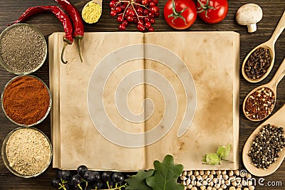 Open vintage book with spices on wooden background. Healthy vegetarian food. Recipe, menu, mock up, cooking. Stock Photo
