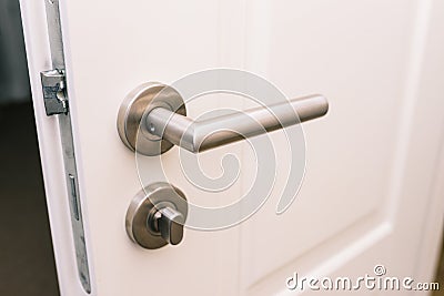 Open the white door. Modern chrome handle in your hotel room or home. Entrance to an apartment, office, or bedroom. Door detail. Stock Photo