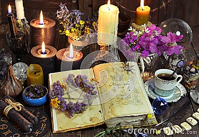 Open witch book with spells, black candles and cup of coffee. Stock Photo