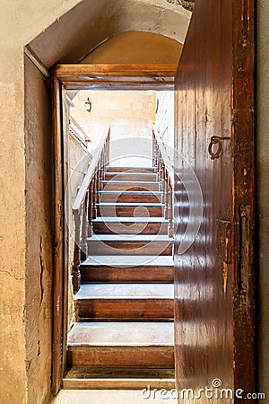 Open wooden door revealing wooden old staircase going up with with reflections of the stairs on the door Stock Photo