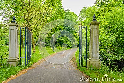 Open wrought iron gate between two stone pillars Stock Photo