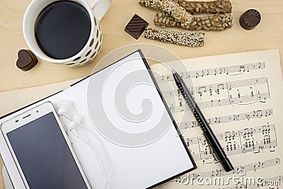 Opened blank notebook with smartphone, cup of coffee and music notation book Stock Photo