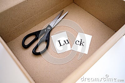 Opened the box and there are scissors and the word luck is cut into two parts Stock Photo