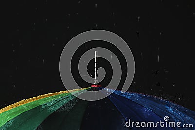 Opened color umbrella under rain against black background Stock Photo