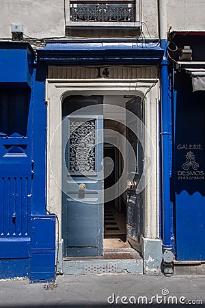 Opened door to old house of Paris France. Antique building exterior with bright blue painted wooden panels. French street facades. Editorial Stock Photo