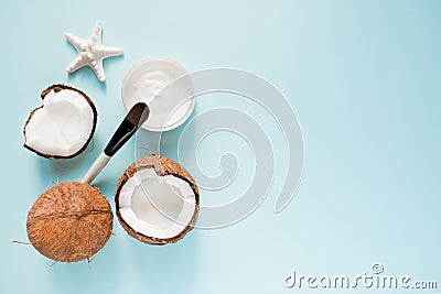 Opened glass jar with fresh coconut oil and ripe coconuts on blue background. Organic healthy food concept. Beauty and SPA concept Stock Photo