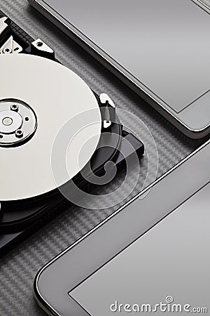 Opened hard disk drive and modern mobile devices on carbon background Stock Photo