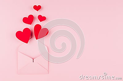 Opened paper envelope with fly out red hearts on soft pink color background. Copy space. Valentine day concept for design. Stock Photo