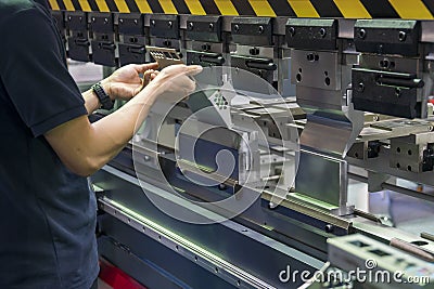 Operation of hydraulic bending machine with forming die by skill operator, The sheet metal manufacturing process . Stock Photo
