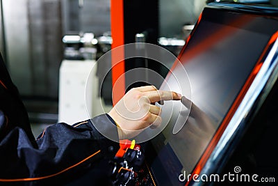 Operator adjusts CNC machine using touch screen Stock Photo