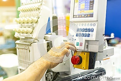Operator or tailor working on control panel of modern and automatic high technology sewing or embroidery machine for textile - Stock Photo