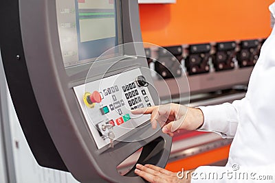 Operator using an industrial CNC machine control panel with precision and focus in a manufacturing environment Stock Photo