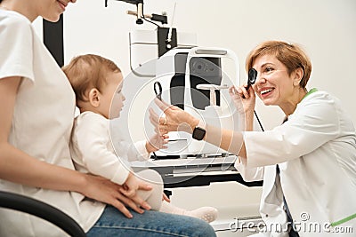 Ophthalmologist performing vision screening in child at initial consultation Stock Photo