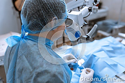 Ophthalmologist surgeon looking through surgical microscope doing difficult operation Stock Photo