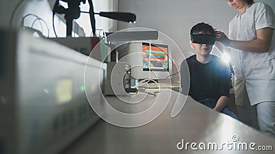 Ophthalmology doctor checks the boy`s vision with the help of stereovideo virtual reality glasses Stock Photo