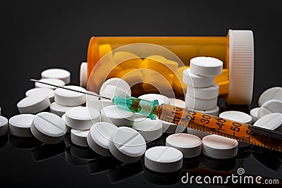 Opioid epidemic and drug abuse concept with a heroin syringe or other narcotic substances next to a bottle of prescription opioids Stock Photo