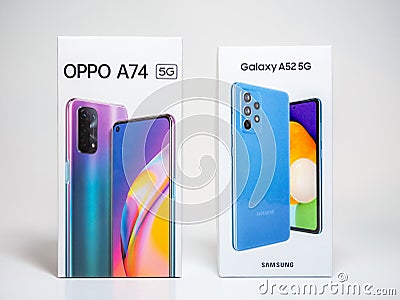 Oppo A74 5G, Samsung A52 5G. Hand placing two brand new android smartphone boxes, mobile device packages closeup, panning shot Editorial Stock Photo