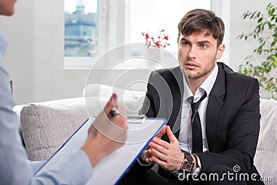 Oppressed man talking with psychologist Stock Photo