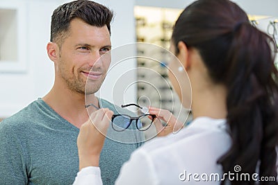 optician fitting glasses onto handsome male customer Stock Photo