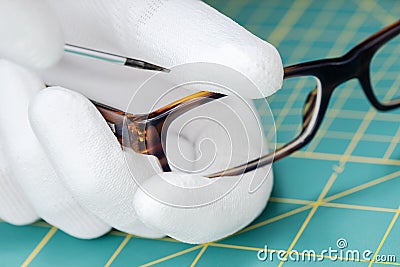 Optician hands repairing eyeglasses with a tool Stock Photo