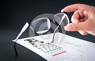 Optician holding glasses. Eyesight test chart in the background. Stock Photo