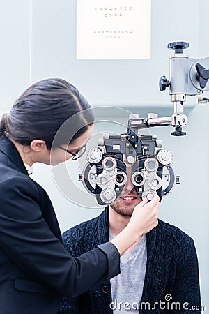 Optician and man at eye examination with phoropter Stock Photo