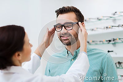 Optician putting on glasses to man at optics store Stock Photo