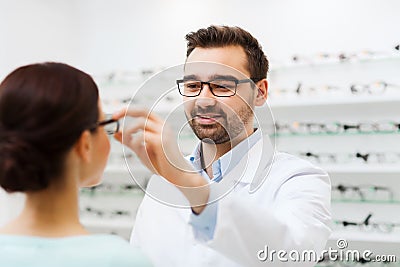 Optician putting glasses to woman at optics store Stock Photo