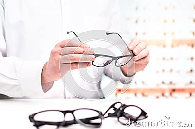 Optician in store holding glasses. Eye doctor with lenses. Stock Photo